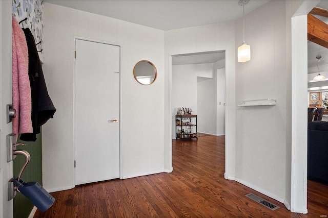 corridor featuring visible vents, baseboards, and wood finished floors