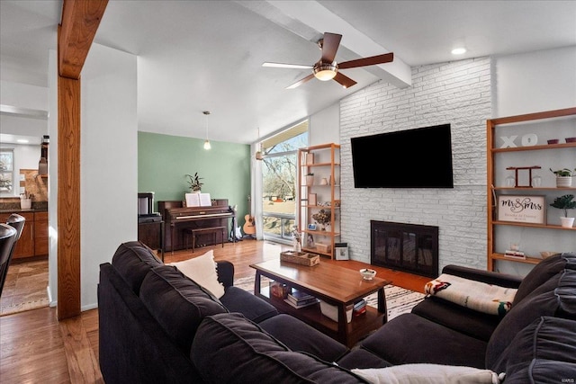 living area featuring a wealth of natural light, a fireplace, lofted ceiling with beams, and wood finished floors