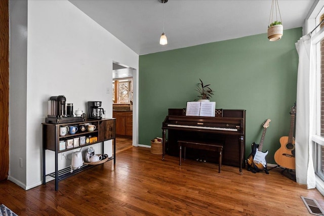 living area with wood finished floors, visible vents, and baseboards