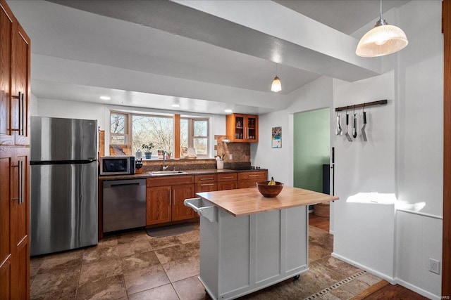 kitchen with backsplash, butcher block countertops, brown cabinets, appliances with stainless steel finishes, and a sink