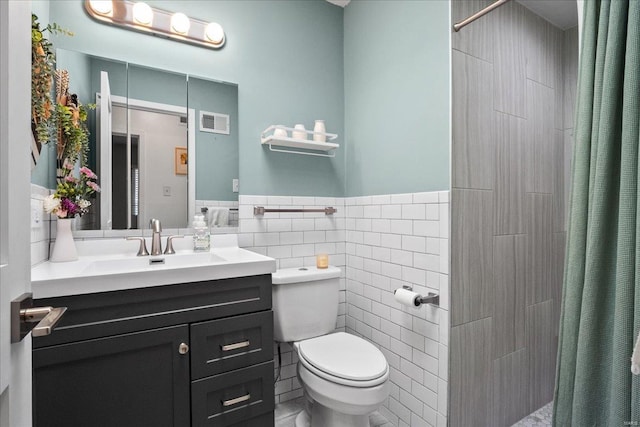 bathroom with visible vents, toilet, a tile shower, tile walls, and vanity