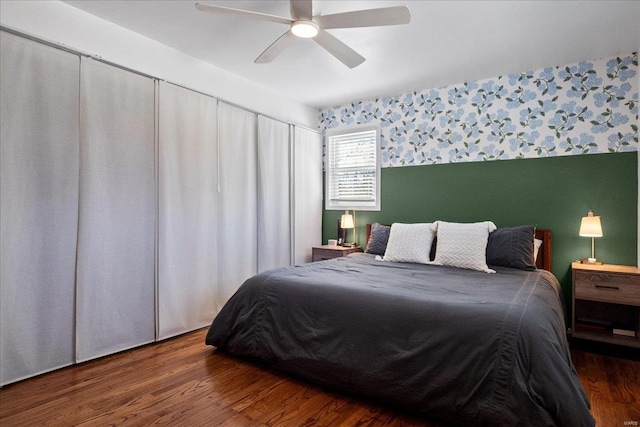 bedroom with wallpapered walls, wood finished floors, and ceiling fan