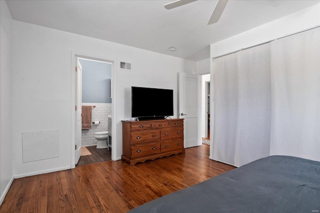 bedroom featuring a ceiling fan, ensuite bath, wood finished floors, and visible vents