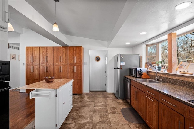 kitchen featuring decorative light fixtures, a kitchen breakfast bar, brown cabinetry, stainless steel appliances, and a sink