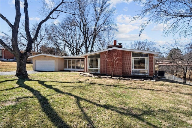 mid-century inspired home with driveway, a front lawn, a sunroom, brick siding, and a chimney