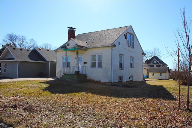 view of front of home featuring a front yard, roof with shingles, and a chimney