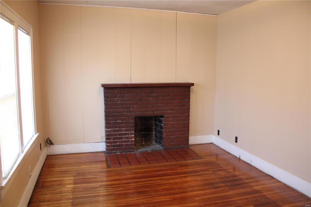 unfurnished living room with a fireplace, baseboards, and wood finished floors