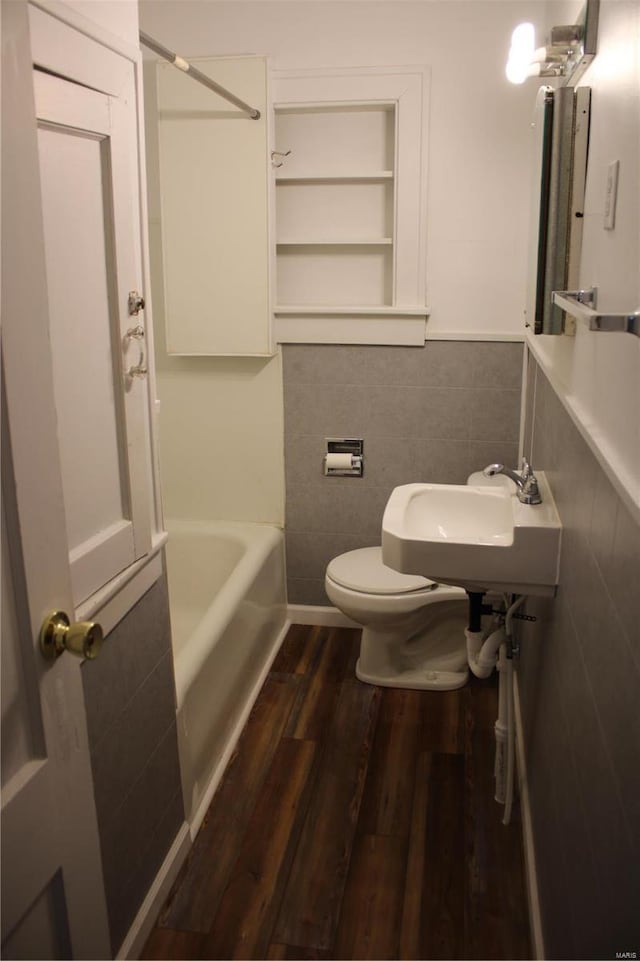 bathroom featuring a sink, wood finished floors, toilet, and tile walls