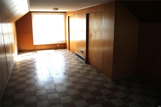 additional living space featuring lofted ceiling, visible vents, and wood walls