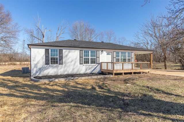 view of front facade featuring cooling unit, brick siding, a wooden deck, and a front lawn