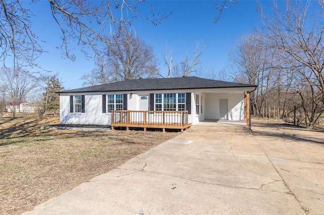 ranch-style house featuring concrete driveway, a shingled roof, and a front yard