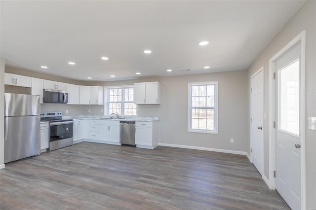 kitchen featuring light countertops, appliances with stainless steel finishes, white cabinetry, a sink, and wood finished floors