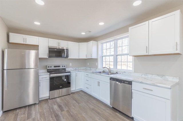 kitchen featuring stainless steel appliances, light wood finished floors, and white cabinets