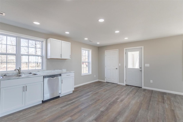 kitchen featuring light wood finished floors, baseboards, white cabinets, stainless steel dishwasher, and a sink