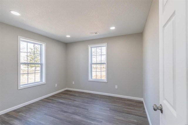 unfurnished room with a textured ceiling, baseboards, and dark wood-style flooring