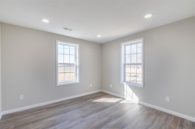 spare room with recessed lighting, wood finished floors, visible vents, and baseboards