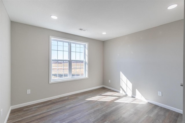 empty room featuring recessed lighting, wood finished floors, visible vents, and baseboards