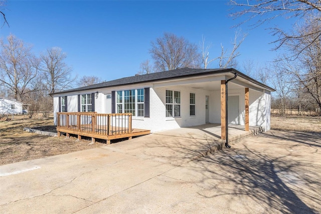 back of house with concrete driveway, brick siding, and a deck