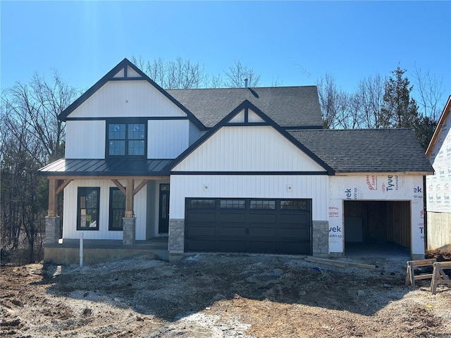 view of front facade with metal roof, a garage, dirt driveway, stone siding, and a standing seam roof