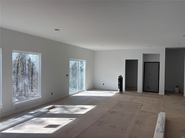 spare room featuring light wood-style floors, plenty of natural light, and baseboards