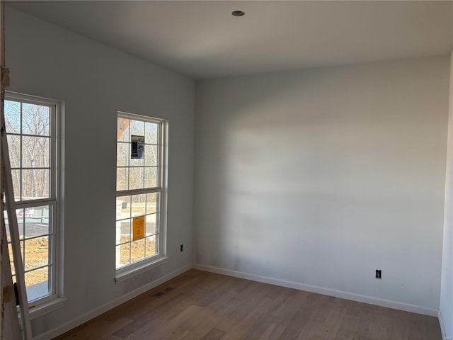 spare room featuring visible vents, baseboards, and wood finished floors