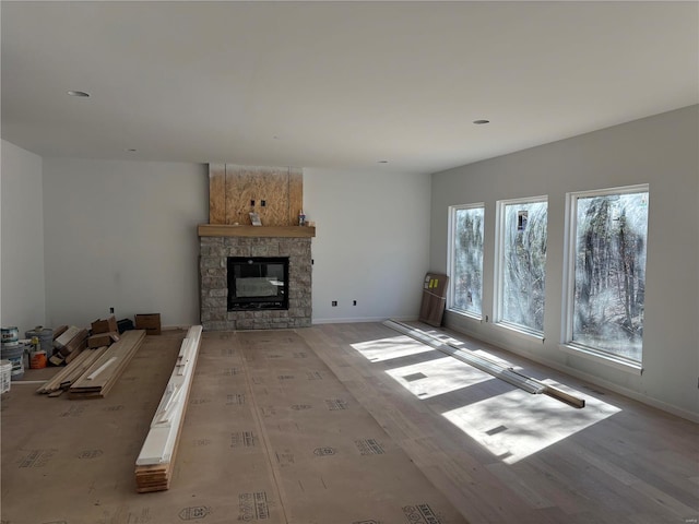 unfurnished living room featuring a fireplace, light wood-style flooring, and baseboards