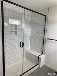 full bathroom with a shower stall and baseboards