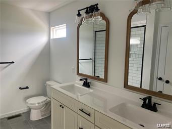 bathroom featuring a sink, toilet, and double vanity