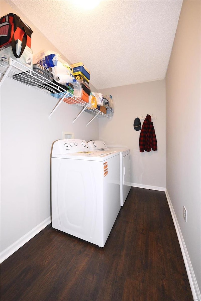 clothes washing area with dark wood-type flooring, a textured ceiling, laundry area, independent washer and dryer, and baseboards