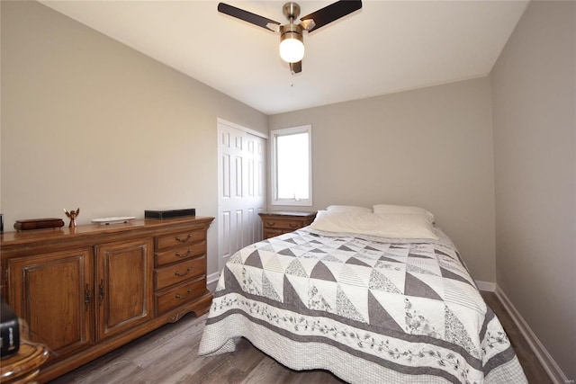 bedroom featuring ceiling fan, a closet, wood finished floors, and baseboards