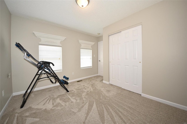 exercise area with a textured ceiling, carpet flooring, visible vents, and baseboards