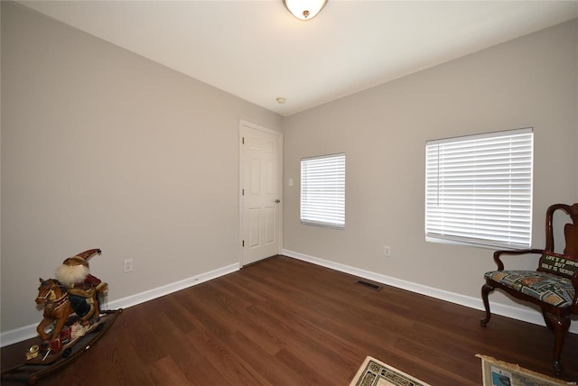 living area featuring dark wood-style flooring, visible vents, and baseboards