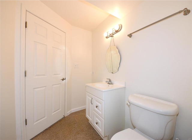 half bathroom with baseboards, vanity, and toilet