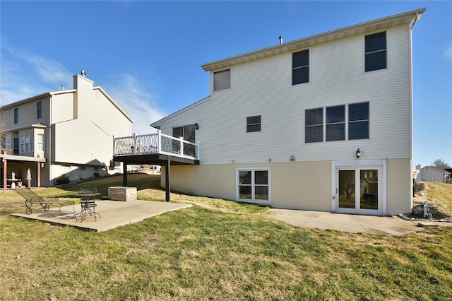 rear view of property featuring a deck, a patio, and a yard