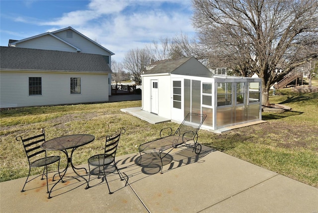 exterior space with an outbuilding, a patio, a shingled roof, and a lawn