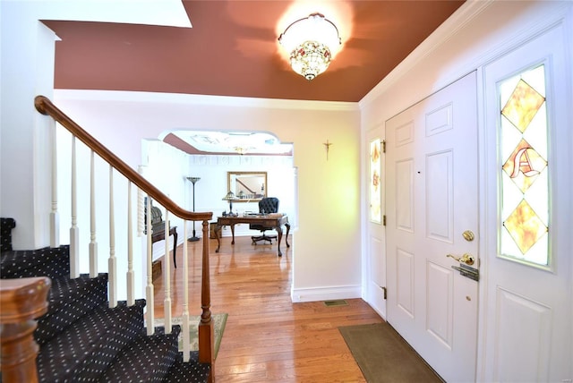 foyer with ornamental molding, stairway, baseboards, and wood finished floors