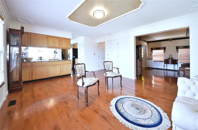 interior space with ornamental molding, visible vents, and wood finished floors