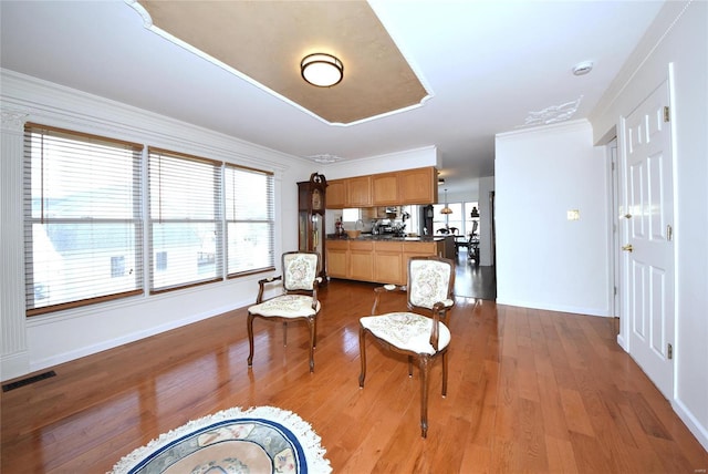 living area featuring baseboards, visible vents, dark wood finished floors, and ornamental molding