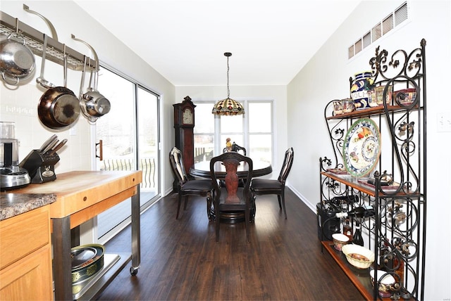 dining area with a wealth of natural light, dark wood-style flooring, visible vents, and baseboards