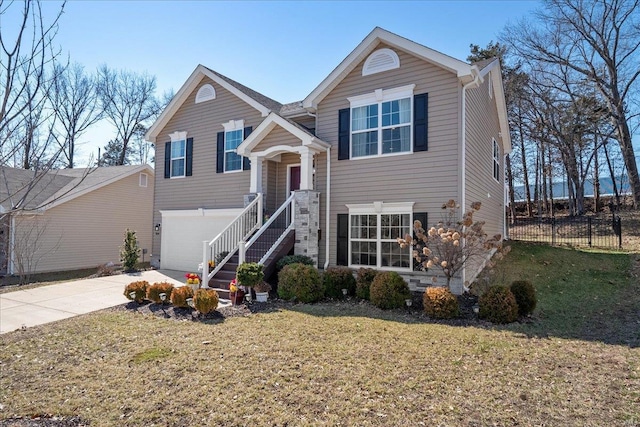 bi-level home featuring driveway, an attached garage, fence, and a front lawn