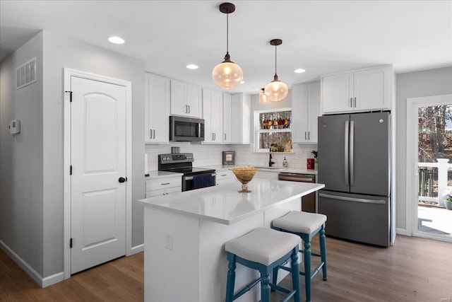 kitchen featuring white cabinets, dark wood-style flooring, stainless steel appliances, and backsplash