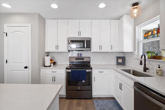 kitchen with appliances with stainless steel finishes, recessed lighting, white cabinetry, and a sink