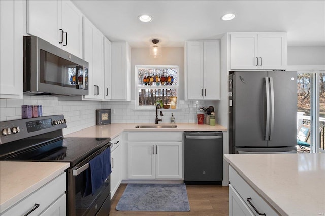 kitchen featuring appliances with stainless steel finishes, white cabinets, a sink, and light countertops