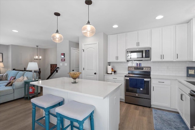 kitchen with backsplash, stainless steel appliances, wood finished floors, and open floor plan