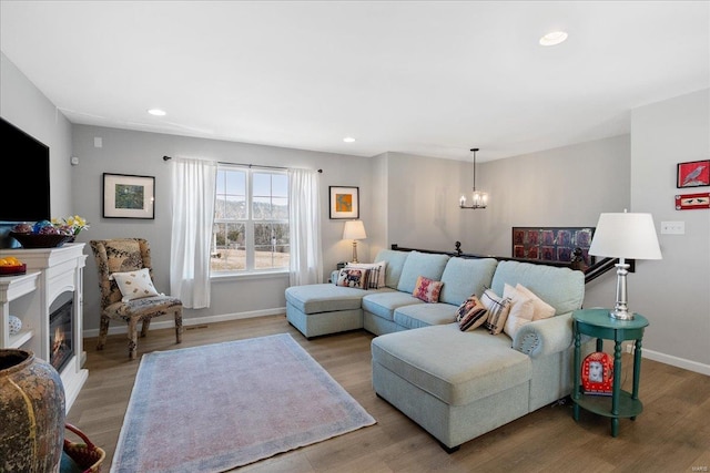 living area with a glass covered fireplace, light wood-style flooring, baseboards, and recessed lighting