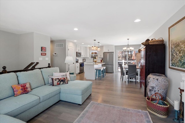 living area with recessed lighting, visible vents, an inviting chandelier, light wood-style floors, and baseboards