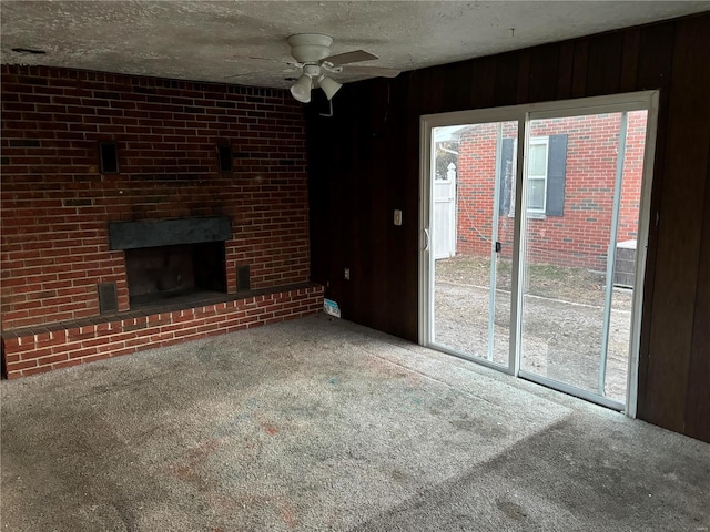 unfurnished living room with a textured ceiling, ceiling fan, carpet, and a brick fireplace