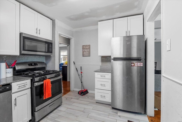 kitchen featuring appliances with stainless steel finishes, light wood-style floors, white cabinets, and decorative backsplash