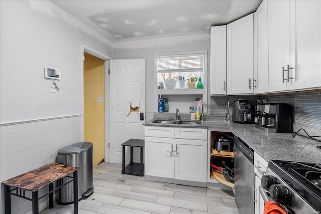 kitchen with tasteful backsplash, white cabinets, appliances with stainless steel finishes, stone counters, and a sink