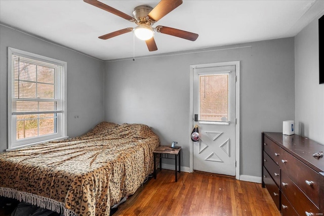 bedroom with ceiling fan, wood finished floors, and baseboards